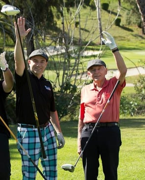 This is a photo of Wellthy member Chris and his dad waving on a golf course