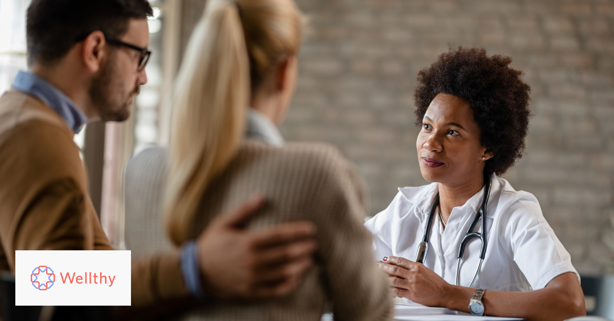 This is a picture of a doctor talking with a couple across a table. 