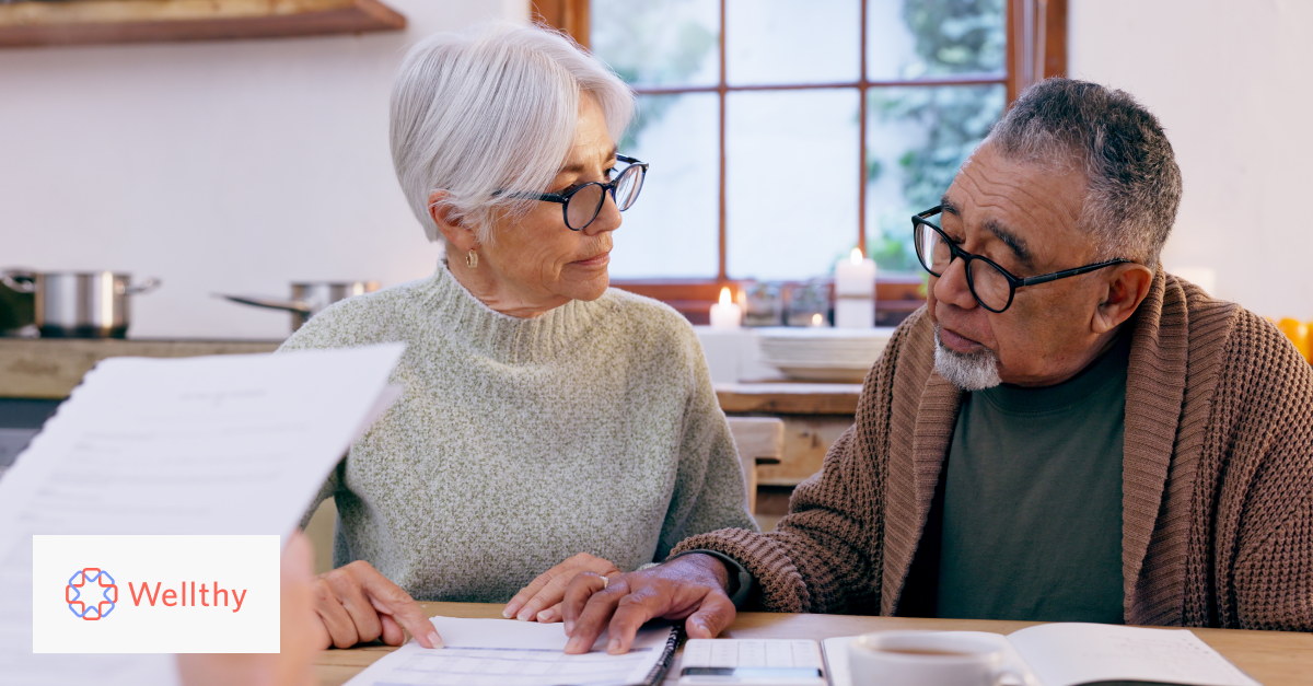 An aging couple sits at a table going over healthcare paperwork.
