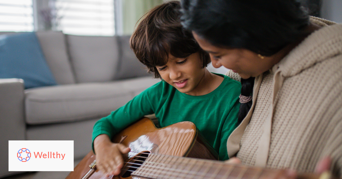 A mother teaching her son how to play the guitar.