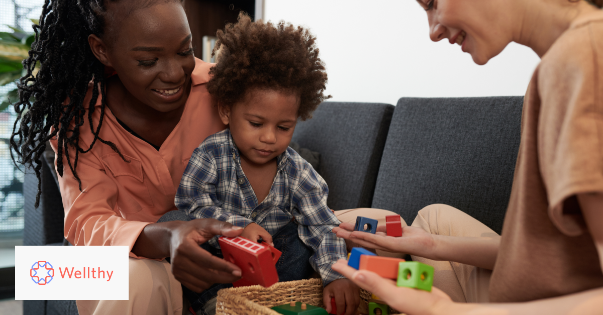 A mom and a caregiver are showing a few toys and games to a child. 
