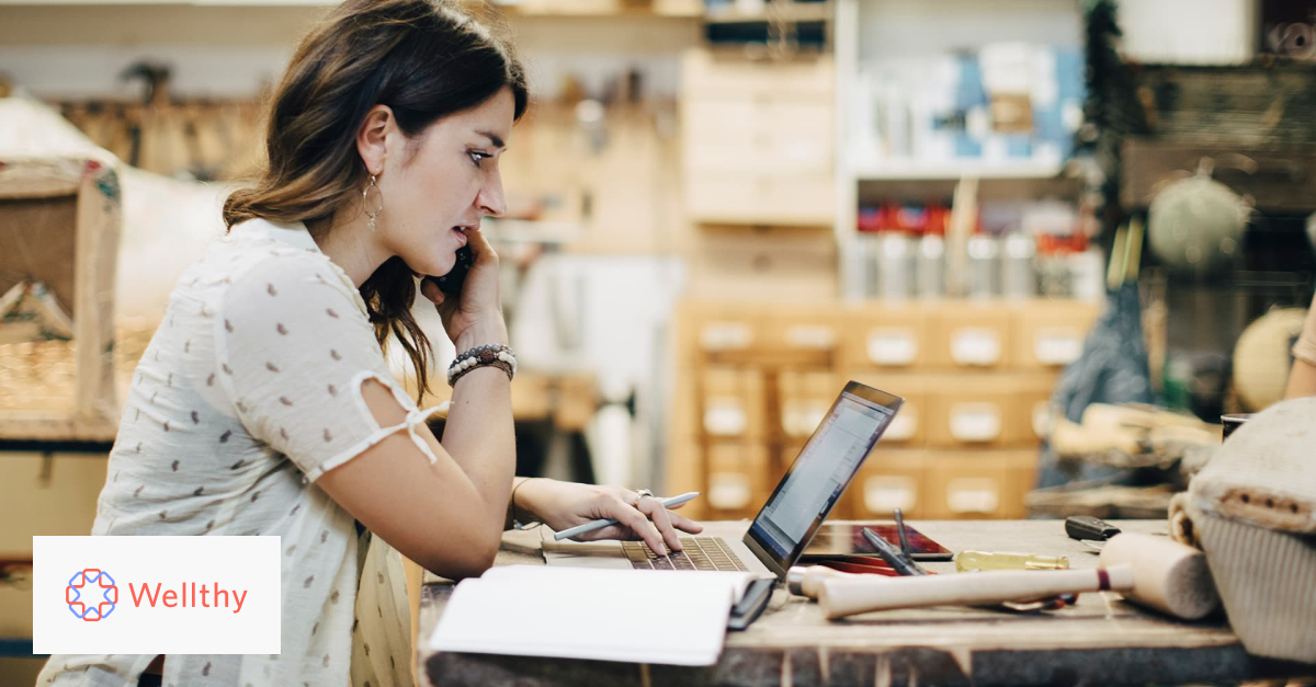 This is an image of a woman working at a laptop in a workspace. 